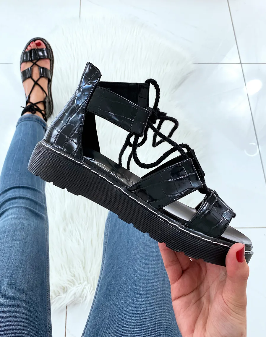 Black flat sandals with ankle ties.